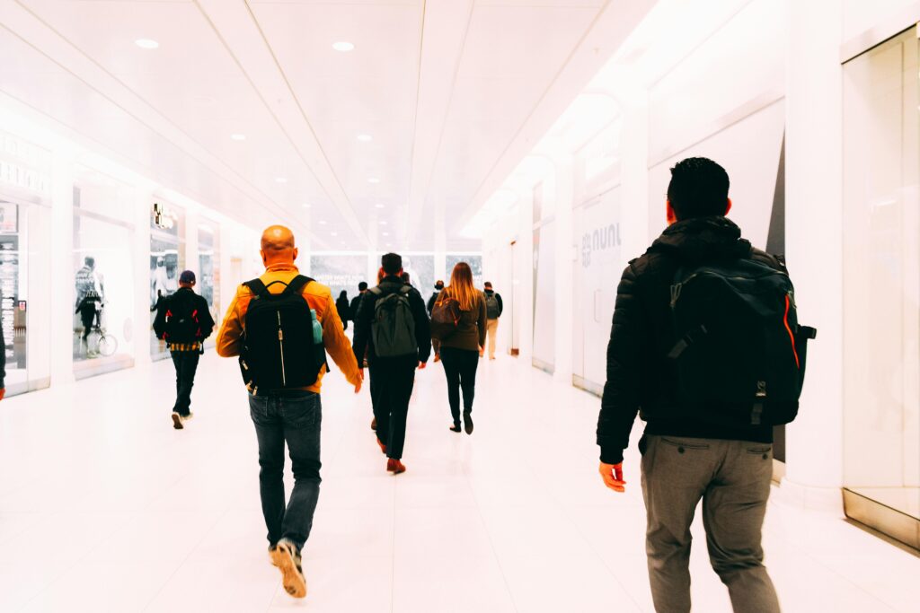 Group of travelers walking through a bright, modern airport terminal carrying backpacks.