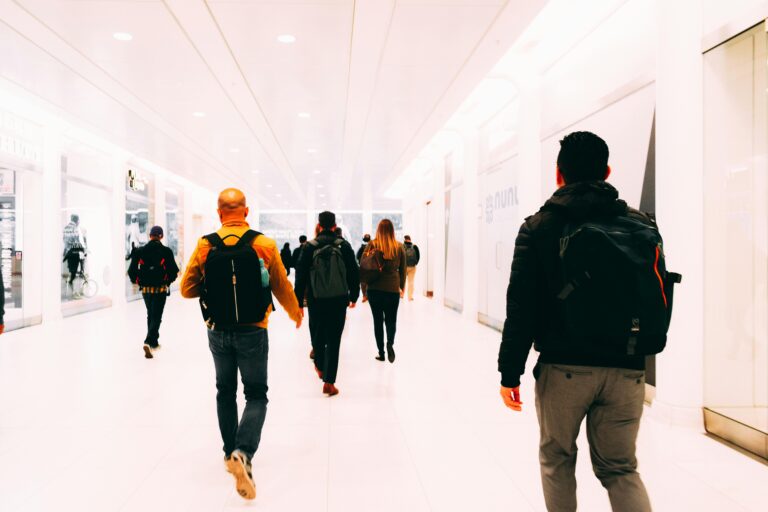 Group of travelers walking through a bright, modern airport terminal carrying backpacks.